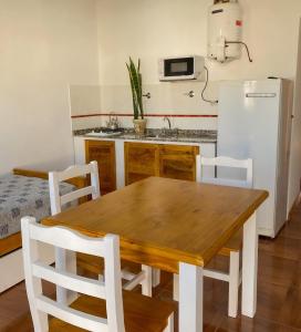 cocina con mesa de madera y nevera blanca en Santa Isabel Departamentos, en Valle María