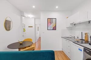 a white kitchen with a blue couch and a table at T2 cosy - stationnement gratuit in Bourg-en-Bresse