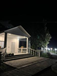 a small white house with a porch at night at MM HOUSE Stepanavan in Stepʼanavan