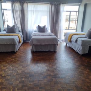Un dormitorio con dos camas y una gran ventana. en Colchester flat, en Durban