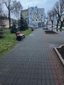 ein Park mit einer Bank und ein Gebäude mit einem Wandbild in der Unterkunft Квартира в центральній частині Луцька in Luzk