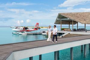 un uomo e una donna in piedi su un molo con un aereo di Le Meridien Maldives Resort & Spa ad Atollo Lhaviyani Altre 142 foto