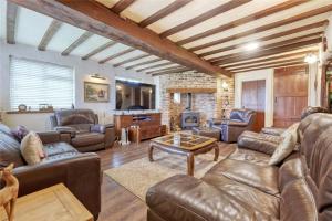 a living room with leather furniture and a fireplace at Blackbrook Farmhouse in Colchester