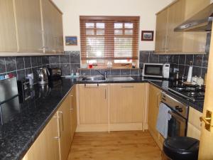 a kitchen with wooden cabinets and black counter tops at Dullatur in Newtonmore