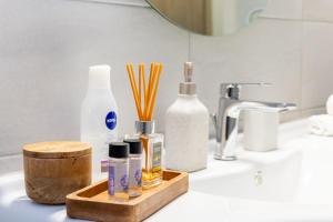a bathroom counter with a sink with soap and cosmetics at P&K LUXURY APARTMENTS 2 in Kalamata +7 photos