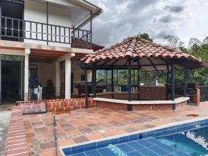 a pavilion with a pool in front of a house at Finca la mariana in Pereira