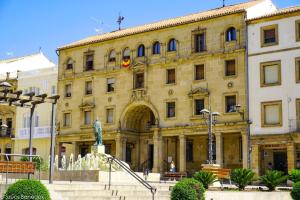 a large building with a statue in front of it at Apartamentos de Don Juan in Úbeda