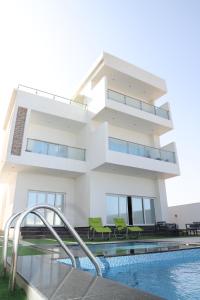 a house with a swimming pool in front of it at شالية ماربيا الاشخرة Marbella Ashkhara Chalet in Al Ashkharah
