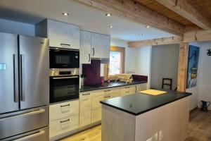 a kitchen with a stainless steel refrigerator and cabinets at Magnifique chalet Nordique à La Féclaz - Idéal pour 6 personnes in La Féclaz