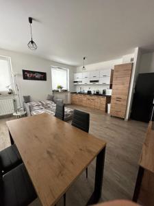 ein Wohnzimmer mit einem Holztisch und einer Küche in der Unterkunft Apartament z tarasem in Sanok