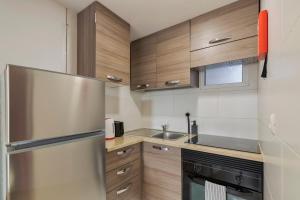 a kitchen with wooden cabinets and a stainless steel refrigerator at City Life in Setubal +16 photos