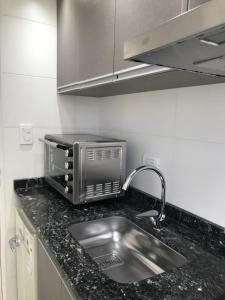 Una encimera de cocina con fregadero y microondas. en J-M-L DEPARTAMENTO 5a, en Monte Hermoso