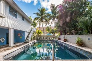 a swimming pool in front of a house with palm trees at Seabreeze A in Holmes Beach