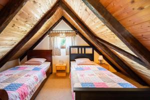 two beds in a attic bedroom with wooden ceilings at Oazena , Authentic house in peaceful village in Selnica +10 photos