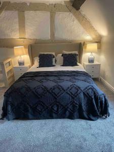 a bedroom with a large bed with blue comforter and two lamps at Penddol Cottage & Boathouse in Llangollen +32 photos