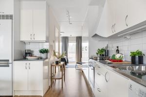 a kitchen with white cabinets and a counter top at Guestly Homes - Elite Studio Apartment in Nyköping