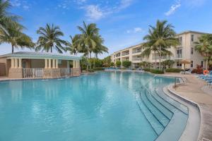 a swimming pool at a resort with palm trees at Deja Blue at Mariner's Club, 2 Pools, Fitness Center, Marina and more in Key Largo
