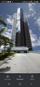a large building with a palm tree in front of it at Flat no Beach Class Internacional, à beira-mar, em Boa Viagem, Recife-PE, com portaria e restaurante 24h - ideal para concursos, turismo, visto americano e jogos da série A - Piscina em reforma in Recife