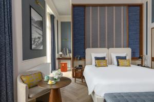 ein Schlafzimmer mit einem Bett, einem Stuhl und einem Tisch in der Unterkunft Hôtel Métropole Genève in Genf