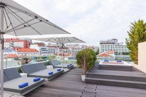 a rooftop deck with lounge chairs and umbrellas at Altis Prime Hotel in Lisbon