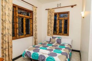 a bedroom with a bed and two windows at Mara Home 1 in Arusha