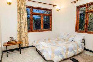 a bedroom with a bed and a table and windows at Mara Home 1 in Arusha