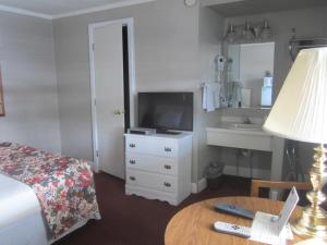 a hotel room with a bed and a tv and a table at Big Horn Motel in Buffalo