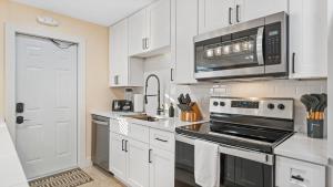 a kitchen with white cabinets and a microwave at The Shark Tank Cocoa Beach - Retro Florida, Downtown, 5-Min Walk to Beach, Shops & Bars in Cocoa Beach
