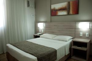a bedroom with a large bed and two night stands at Hotel Linhatur in Linhares