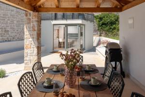 a table with a vase of flowers on a patio at Beeindruckende Steinfinca mit privatem Salzwasserpool, Panoramablick aufs Meer, Grill in Orbani