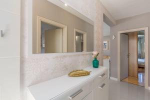 ein weißes Badezimmer mit Waschbecken und Spiegel in der Unterkunft Lichtdurchflutetes Apartment nur 500 Meter zum Strand mit privater Terrasse in Funtana + 16 Fotos