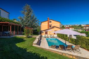 a house with a swimming pool with chairs and an umbrella at Faszinierendes Ferienhaus mit Privatpool, Volleyballfeld, Fussballplatz, Trampolin beim bekannten Radweg Parenzana in Vižinada