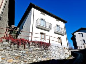 a white building with red plants on a stone wall at Quigna 29 in Tresenda