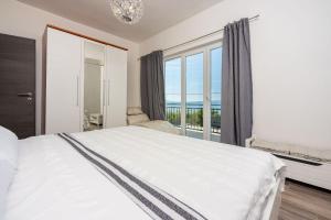德拉马利Beeindruckendes Apartment mit Whirlpool, Lounge-Liegen, Meerblick, Grill的卧室里有一张白色的床和一扇大窗户
