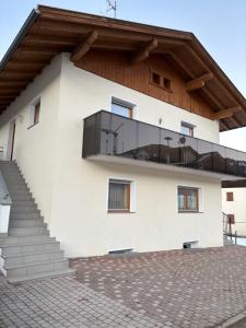 a white building with a balcony with a roof at Appartements Schatzer in Valdaora