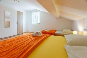 Cette chambre comprend 2 lits avec une couverture orange et jaune. dans l'établissement Ruhiges Apartment mit Holzkohlegrill, Pool mit Whirlpoolfunktion, Waschmaschine, Trockner, à Grižane 21 autres photos
