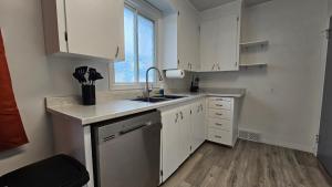 a kitchen with white cabinets and a sink and a window at Retro Retreat - 3bdr, 1 bath, close to city center in Edmonton