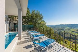 a balcony with blue chairs and a swimming pool at Modernes Apartment mit traumhafter Aussicht, Pool, Privatparkplatz, WiFi in Pazin