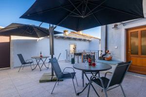 two tables and chairs with umbrellas on a patio at Modernes Apartment mit traumhafter Aussicht, Pool, Privatparkplatz, WiFi in Pazin