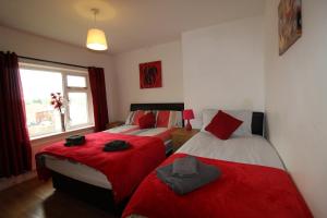 Un dormitorio con dos camas con sábanas rojas y una ventana. en Byron House, en Chesterfield
