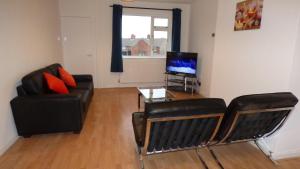 Una sala de estar con un sofá, una mesa y un televisor. en Byron House, en Chesterfield