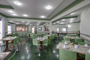 a dining room with tables and green chairs at Flat Itararé Tower Beach in São Vicente