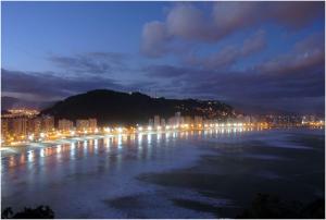 a city at night with lights on the water at Flat Itararé Tower Beach in São Vicente +9 photos