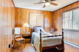 a bedroom with wooden walls and a bed and a fan at Birdwatching, Board Games and BBQs Cabin in Murphy! in Salem