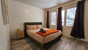 a bedroom with a bed with an orange blanket and a window at Retro Retreat - 3bdr, 1 bath, close to city center in Edmonton
