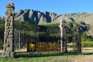 a gate with a sign in front of a mountain at Alem Departamento Tornquist in Tornquist