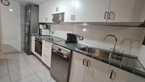 cocina con armarios blancos y fregadero de acero inoxidable en terrace 2BRooms100m2, 3Air Conditions, en Vecindario