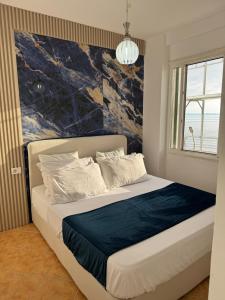 a bedroom with a bed with a painting on the wall at Beach Front Superior Apartment Blue Marine in Durrës