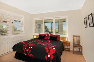 a bedroom with a bed with a black and red blanket at St Raphael in Leura