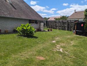 a yard with a fence next to a house at Douceur et quiétude rurale in Lassay-sur-Croisne